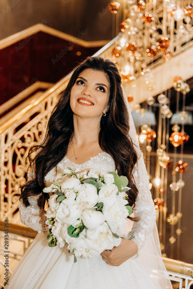 Luxury bride with a bouquet in her hands on a background of exquisite chandelier Luxury bride with a bouquet in her hands on a background of exquisite chandelier