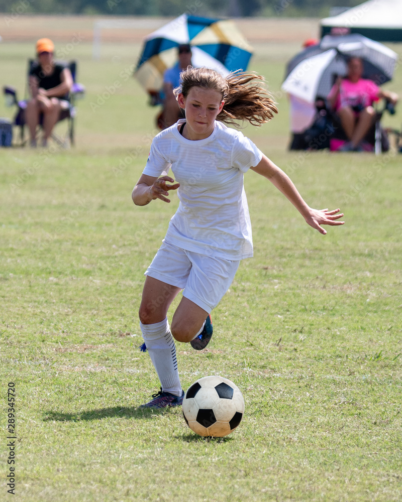 Young athletic teen girl playing in a soccer game Young athletic teen girl playing in a soccer game