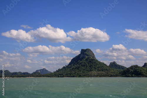 Beautiful beach view on the island with green mountains, white clouds, and blue sky.