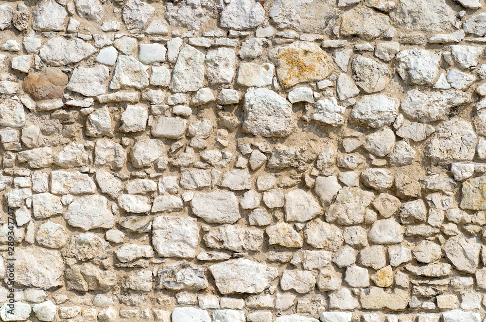 An old time damaged wall made of rough stone. Natural background for design.