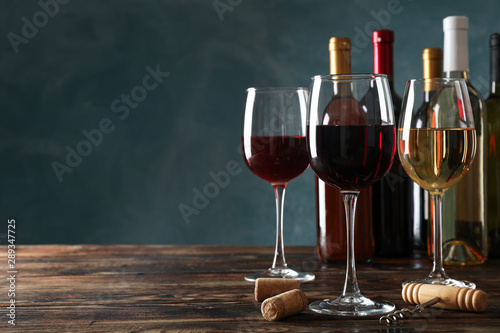 Corkscrew, bottles and glasses with wine on wooden table, copy space