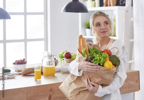 Young woman holding grocery shopping bag with vegetables Standi