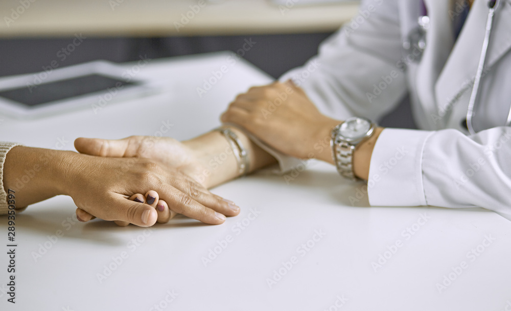 Obraz premium Woman doctor calms patient and holds hand