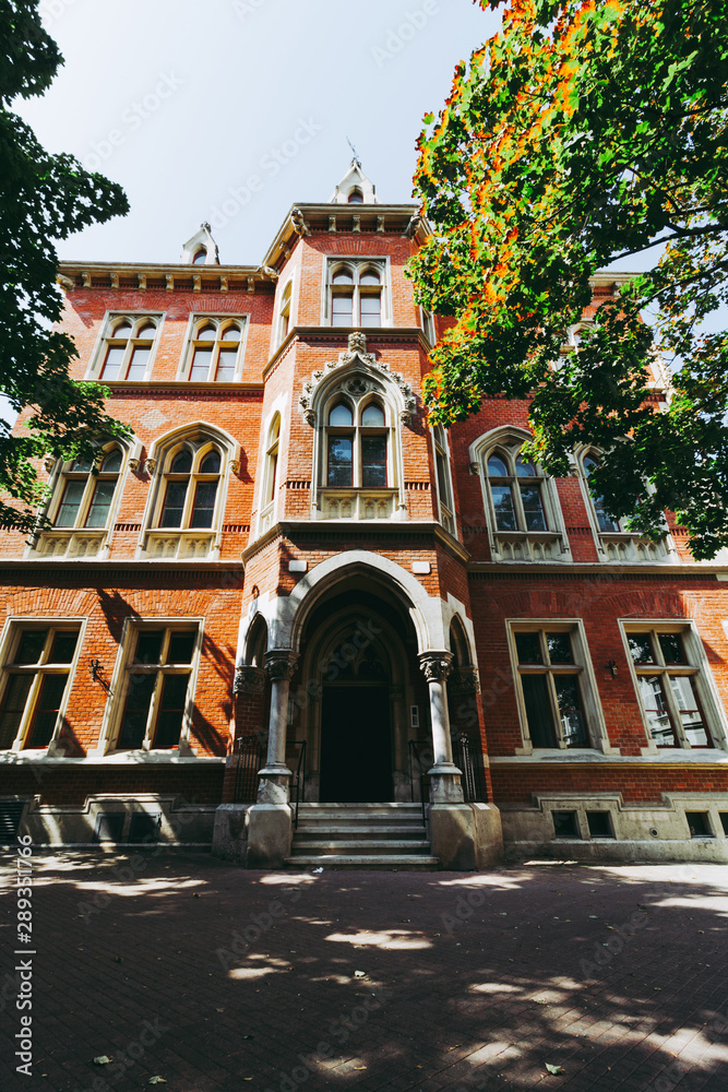 exterior of an old three story red brick building with white columns on ...