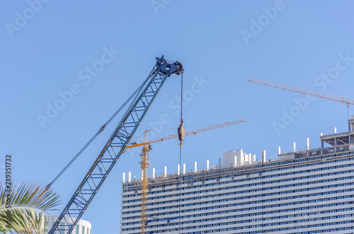 Construction of multi-storey buildings in Batumi. Construction cranes on the background of buildings. Storey building against the blue sky.