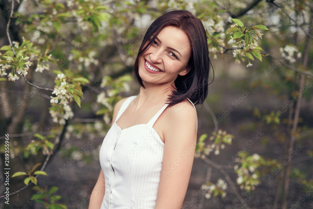 Woman in casual white dress looking at camera in park Woman in casual white dress looking at camera in park