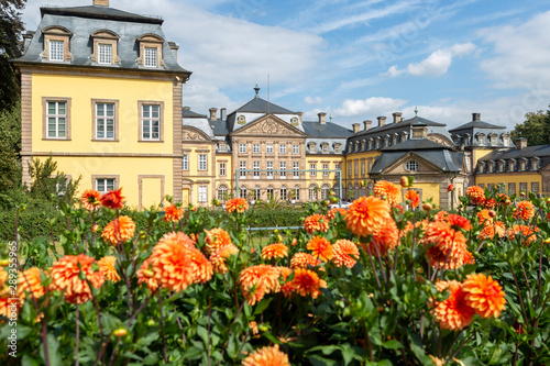 Architecture of the Arolsen castle in Bad Arolsen in the Sauerland region with focus on orange flowers in the foreground against a blue sky