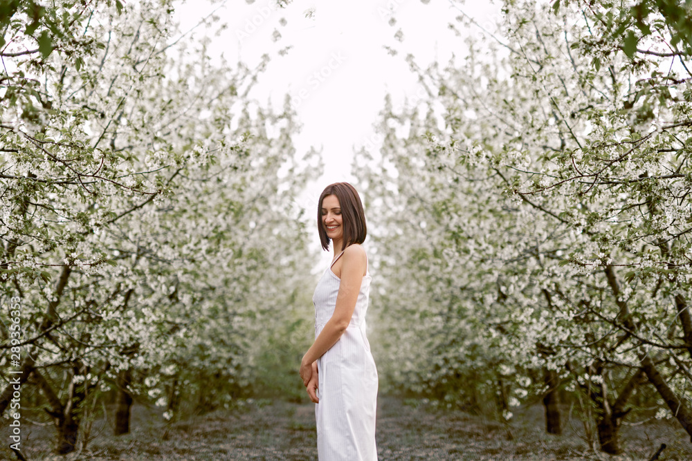 Peaceful stylish woman standing beside blossoming spring trees Peaceful stylish woman standing beside blossoming spring trees