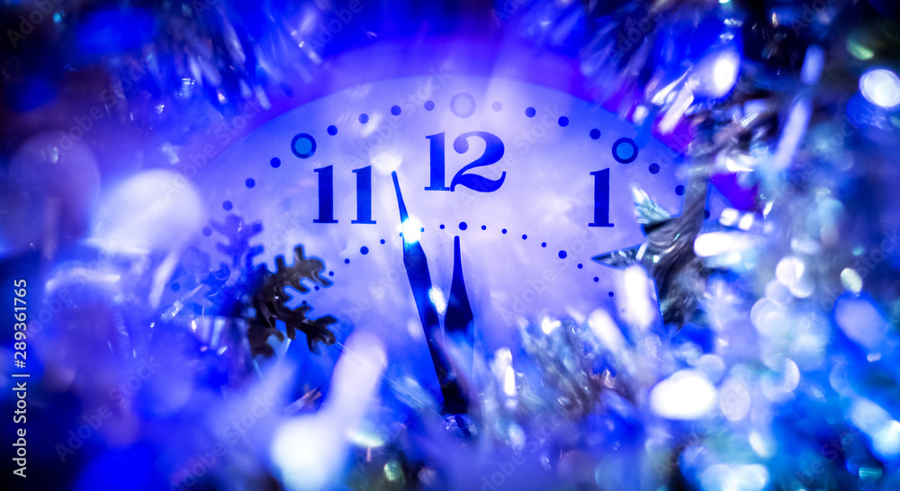 Fototapeta premium The clock hands indicate the approach of the new year. Clock with festive decorations on New Year's night_