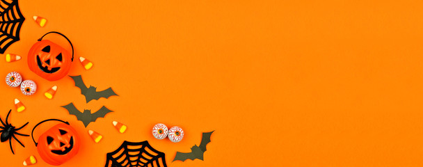 Halloween corner border banner with scattered candy and decor. Flat lay over an orange background with copy space.