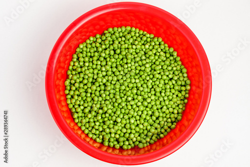 Freeh organic green peas in a large red round bowl isolated on white, top view