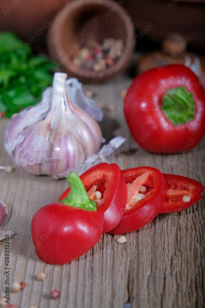 Red bell pepper, garlic, greens, spices on a wooden table. Red bell pepper, garlic, greens, spices on a wooden table.