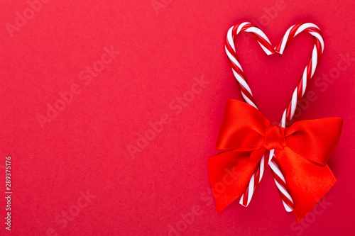 Christmas candy canes, stick and decor on color background. Christmas candy cane heart on an red background.