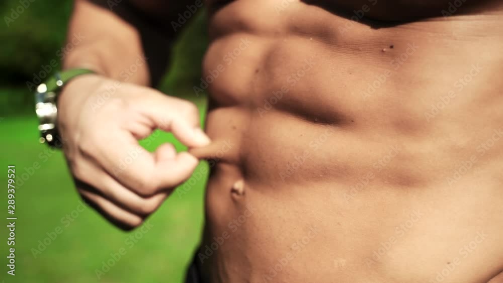 Close-up of perfect six pack torso, shirtless bodybuilder is ready for sport competitions. Hard workout in the gym and amazing muscular abs result. Sportsman stroking his naked strong body on camera