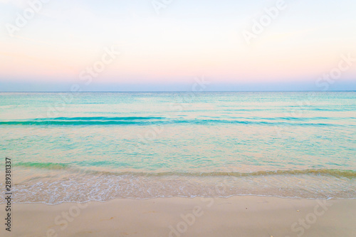 Tropical sea background of pastel sunset skies glowing above tranquil turquoise blue horizon