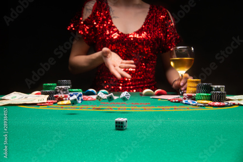 A girl in an evening dress plays in a casino and throws dice, focusing on the dice. Gaming business