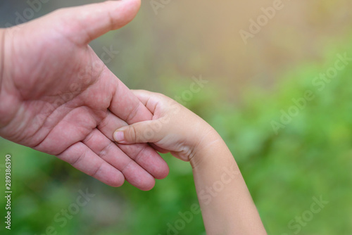 Close-up of father's hand holding his son's hand while outdoors. © stockbob