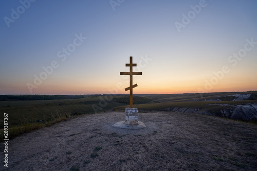 Wooden orthodox cross on the top of Golgotha mountain in the Kostomarovo St. Saviour Monastery at sunset.