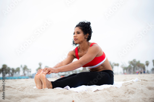 Fotografía Physically fit latina stretches on the beach before working out