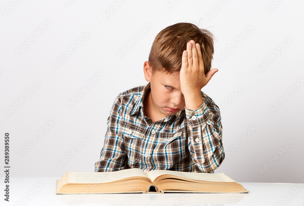 Boy at desk bored tired stressed of reading books. Close-up portrait of Schoolboy Boy at desk bored tired stressed of reading books. Close-up portrait of Schoolboy