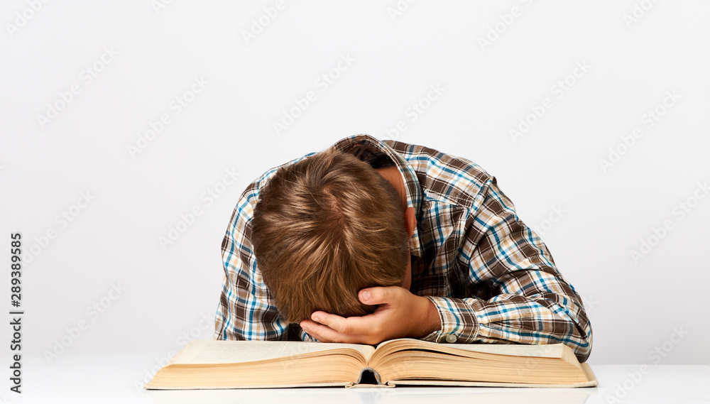 Boy at desk bored tired stressed of reading books. Close-up portrait of Schoolboy Boy at desk bored tired stressed of reading books. Close-up portrait of Schoolboy