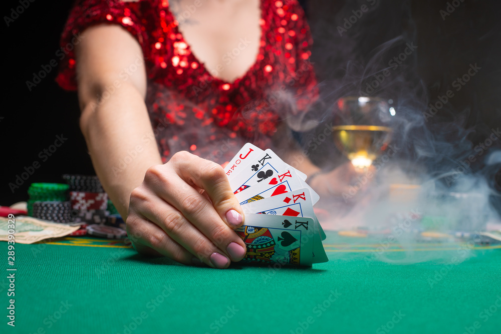 Casino games. A girl in a red evening dress and plays poker in a night casino. covers cards, gaming business