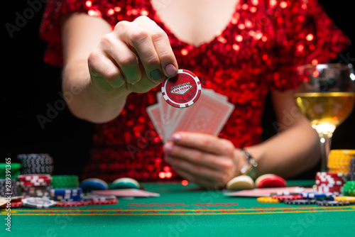 A girl in an evening red dress plays in a casino, holds a chip for a croupier. Gambling business casino