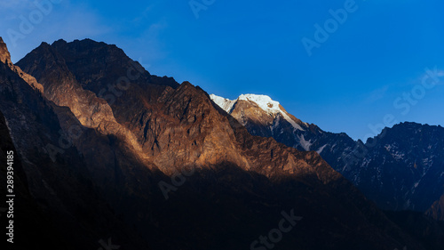 Himalayan mountain in Nepal partly covered with snow, shadow foreground during evening.