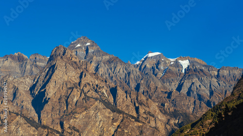 Himalayan mountain partly covered with snow in bright sunny summer day. 