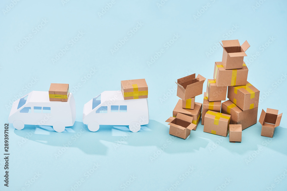 white mini vans near pile of cardboard boxes on blue background white mini vans near pile of cardboard boxes on blue background