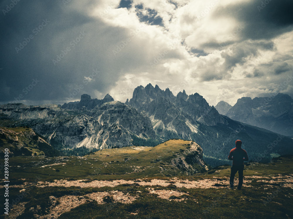 young man enjoying the view of the mountains landscape in the dolomites mountain range.
