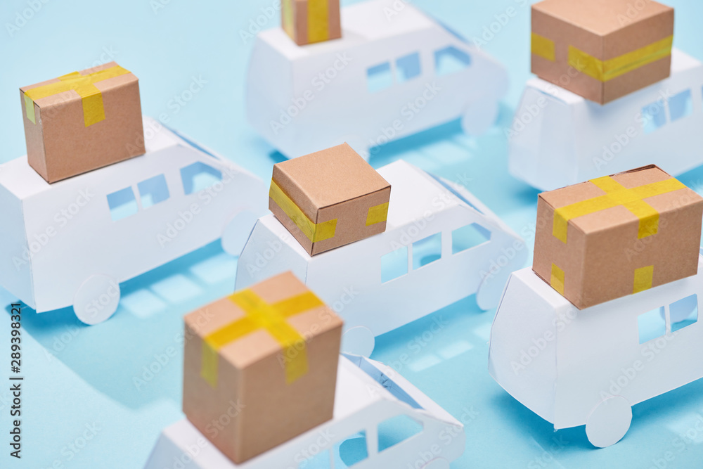 closed cardboard boxes on white mini vans on blue background closed cardboard boxes on white mini vans on blue background