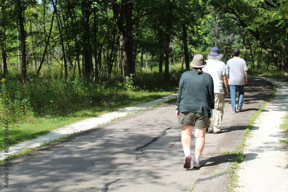 Fototapeta premium Three older people walking on the North Branch Trail at Miami Woods in Morton Grove