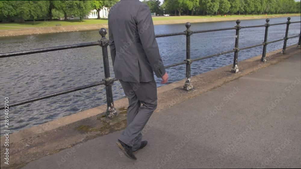 Business man in suit walking commuting to work by the river slow motion