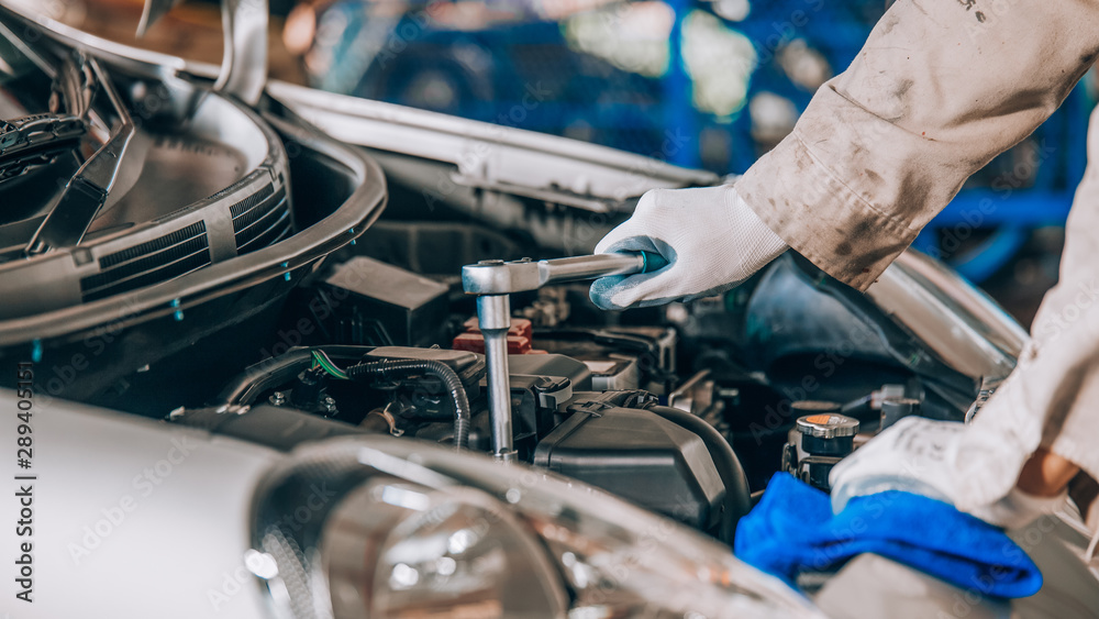 handsome mechanic in uniform is working in auto service. Car repair and maintenance. handsome mechanic in uniform is working in auto service. Car repair and maintenance.