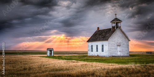Old Rural Church at Sunset with Sunrays Beaming Down From the Sky