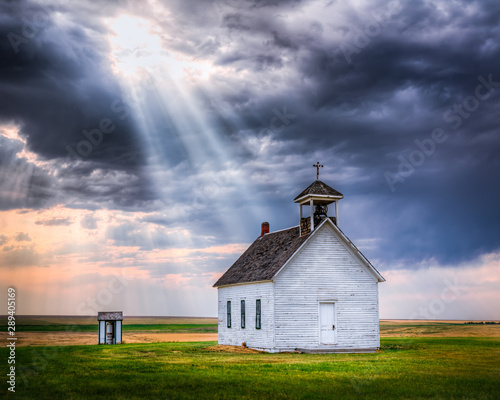 Old Rural Church at Sunset with Sunrays Beaming Down From the Sky