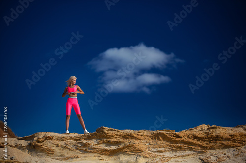 beautiful sporty girl standing on the sand on the beach against the sky
