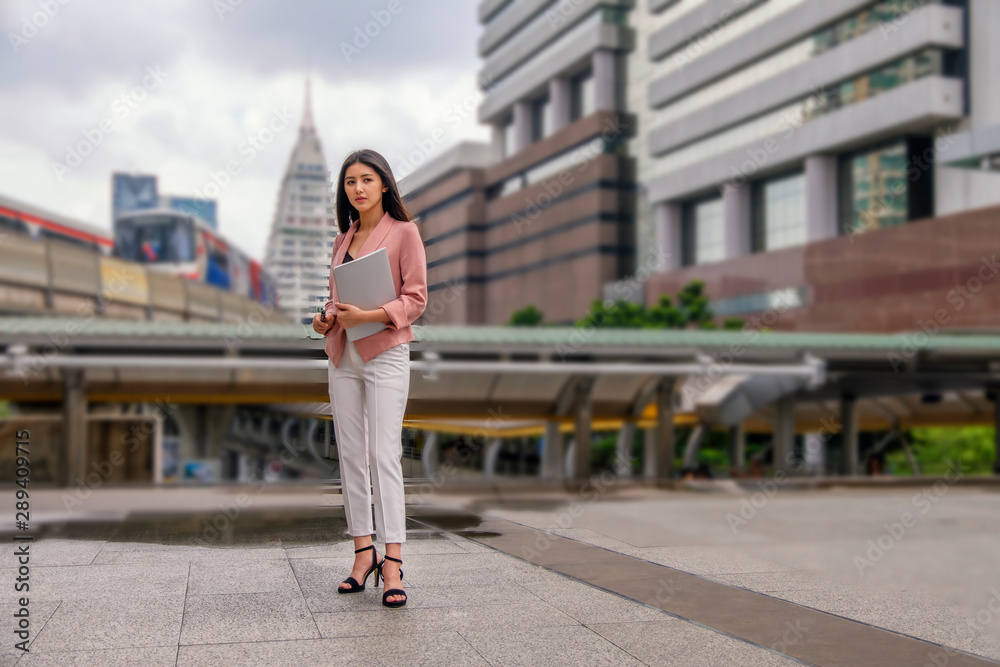 ayoung woman is walking on the street with train background ayoung woman is walking on the street with train background