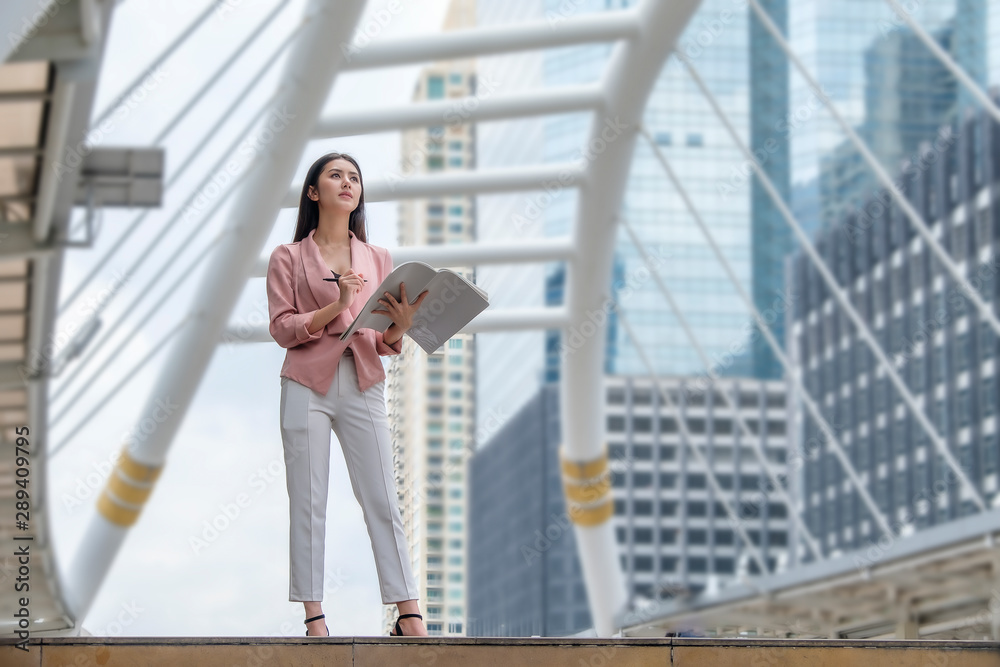 Fototapeta premium a business woman is standing and working in the city