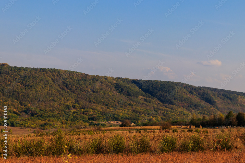 Picturesque autumn scenery with blue sky and colorful autumn trees on mountain hills