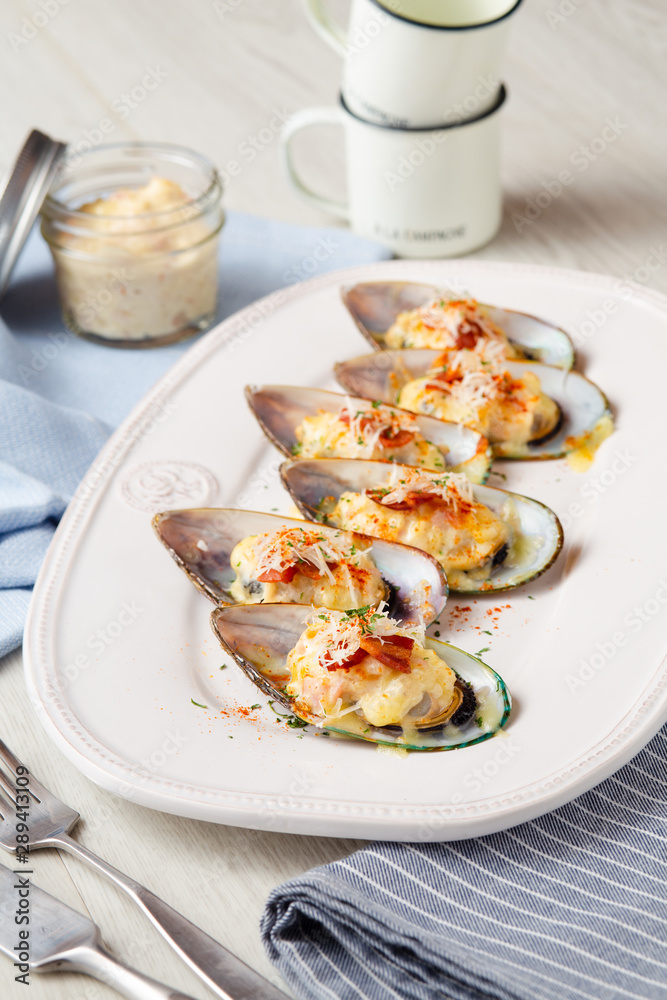 Baked mussels with cheese and bacon on white dish. Baked mussels with cheese and bacon on white dish.
