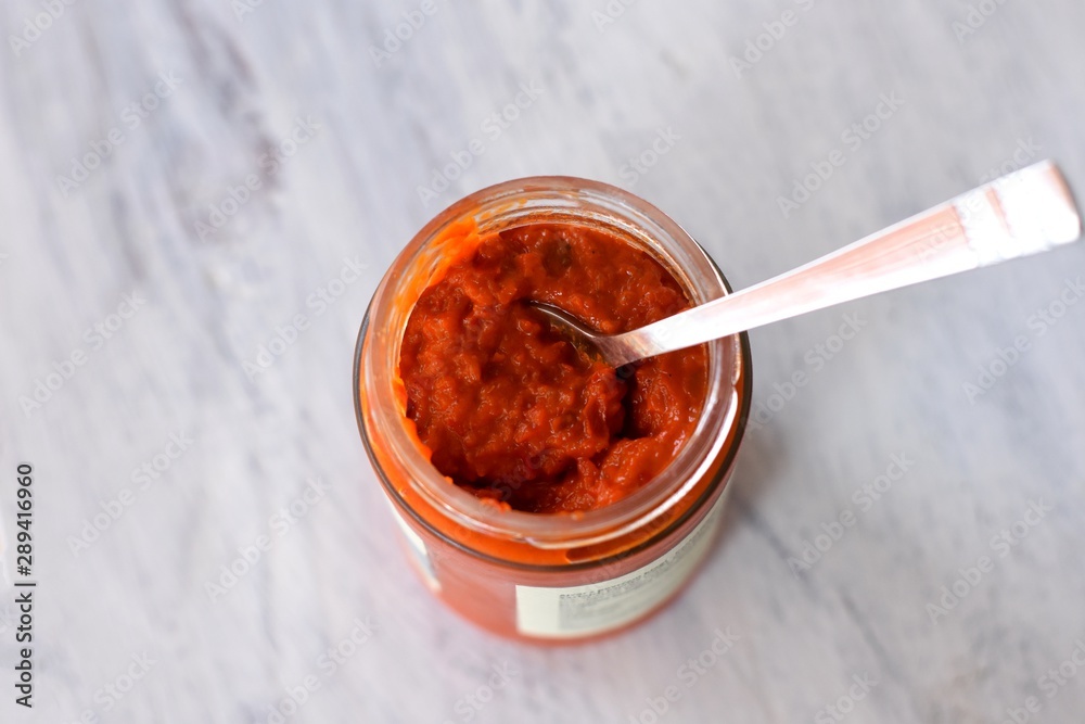 Fototapeta premium Ajvar in a jar, a delicious roasted red pepper and eggplant dish/ Ajvar - traditional Macedonian Serbian dish made from red bell peppers, eggplant and garlic, Lutenitza, popular in Balkans. Homemade