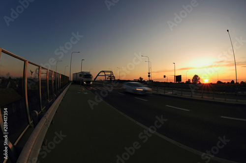 Zachód słońca nad autostradą, samochody, most.