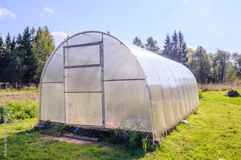 Greenhouse. Bright greenhouse in the garden. Indoor stationary greenhouse Greenhouse. Bright greenhouse in the garden. Indoor stationary greenhouse
