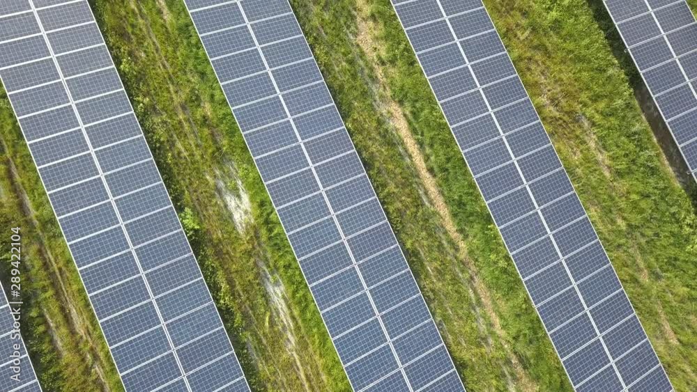 Dynamic aerial video flying close over rows of solar panels in green field Dynamic aerial video flying close over rows of solar panels in green field