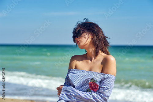 Beautiful young healthy girl in fashionable sunglasses at the seaside . The model wears a blouse and skirt