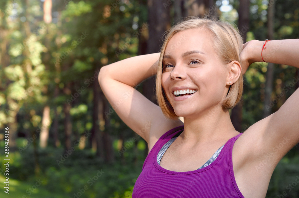 Portrait of young smilling sporty woman stretching in the fores outdoor early in the morning Portrait of young smilling sporty woman stretching in the fores outdoor early in the morning
