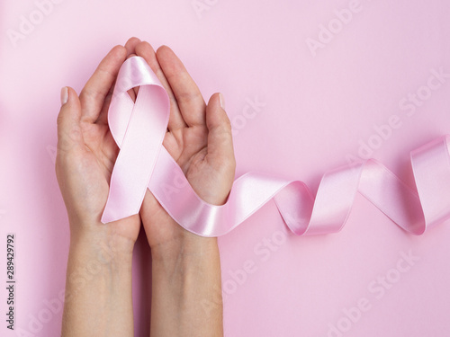 Close-up hands holding pink ribbon