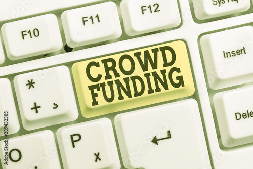 Conceptual hand writing showing Crowd Funding. Concept meaning Fundraising Kickstarter Startup Pledge Platform Donations White pc keyboard with note paper above the white background photo